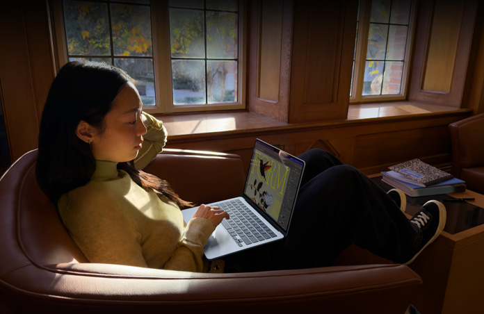 En person som sitter på en stol och använder sin MacBook Air