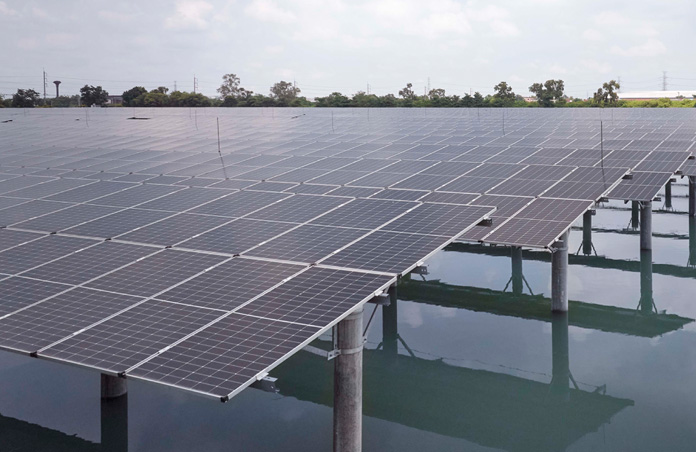 A solar panel array installed over water under a cloudy sky