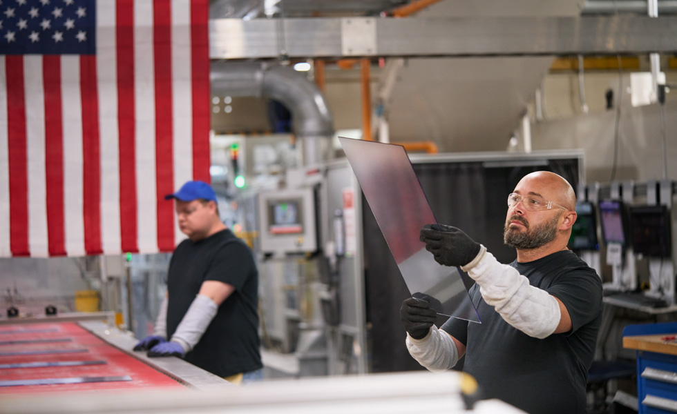 Two employees wearing safety glasses inspect components and production pieces