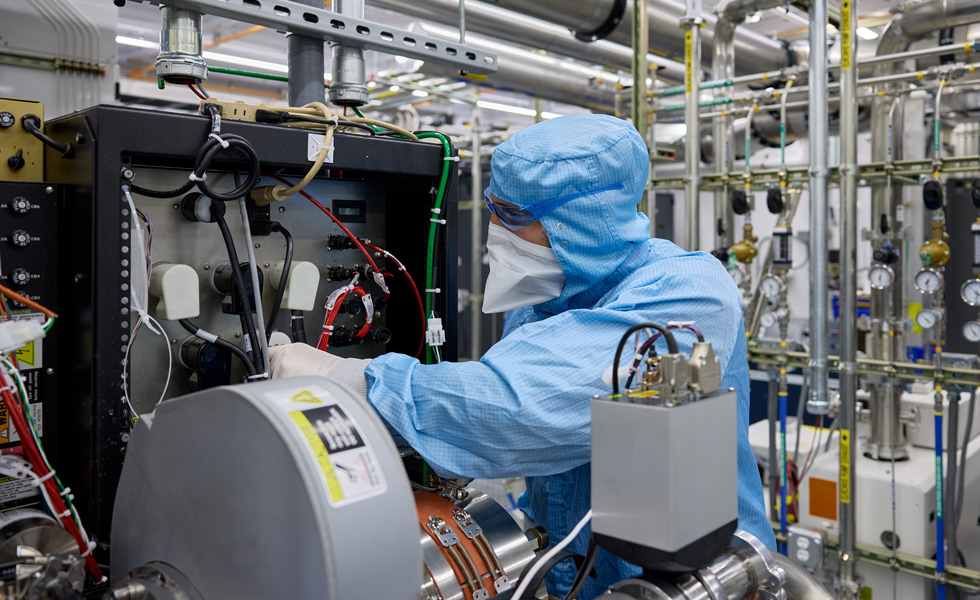 An employee in a full-body work suit inspects machinery